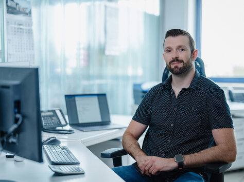 Ein junger Mann sitzt an einem Computer-Arbeitsplatz bei Glasbau Wiedemann aus Augsburg