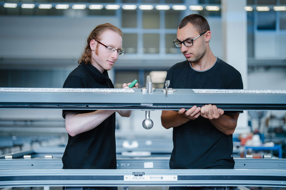 Zwei junge Metallbauer bauen ein Türelement zusammen